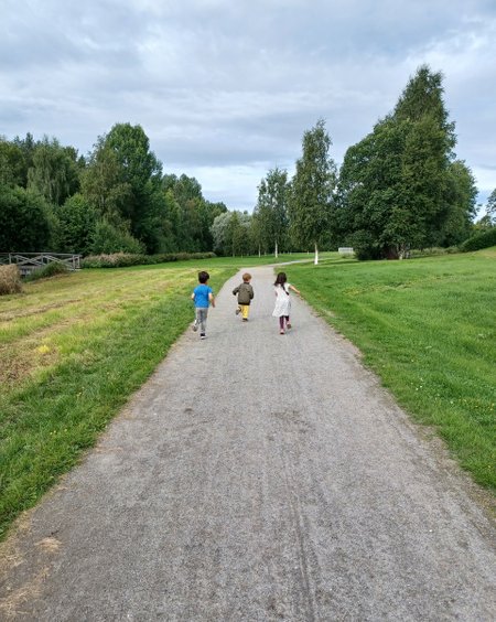 Tre barn springer på lantlig väg på utflykt med förskolan