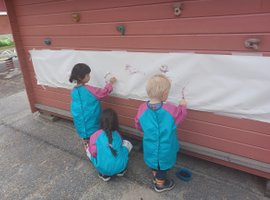 3 barn målar med vattenfärg utomhus på förskolan