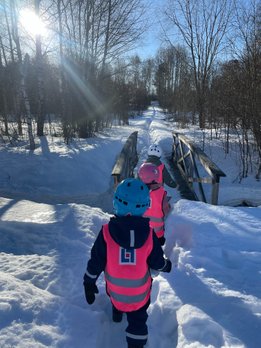 3 barn går över vintrig bro